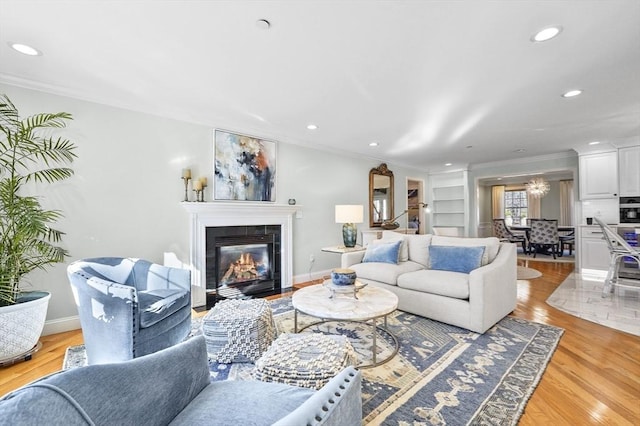living area with ornamental molding, a tile fireplace, recessed lighting, and light wood finished floors