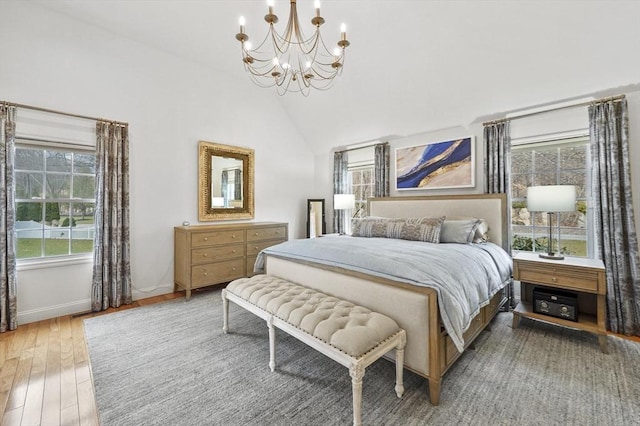 bedroom featuring baseboards, high vaulted ceiling, wood finished floors, and a chandelier
