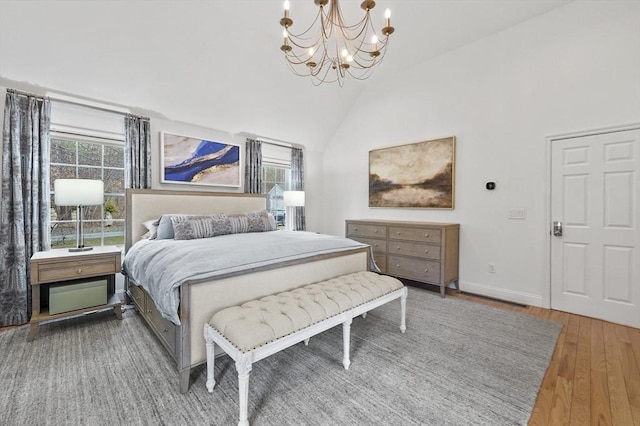bedroom featuring baseboards, high vaulted ceiling, wood finished floors, and an inviting chandelier