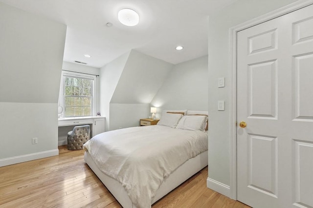 bedroom featuring baseboards, vaulted ceiling, and light wood-style floors