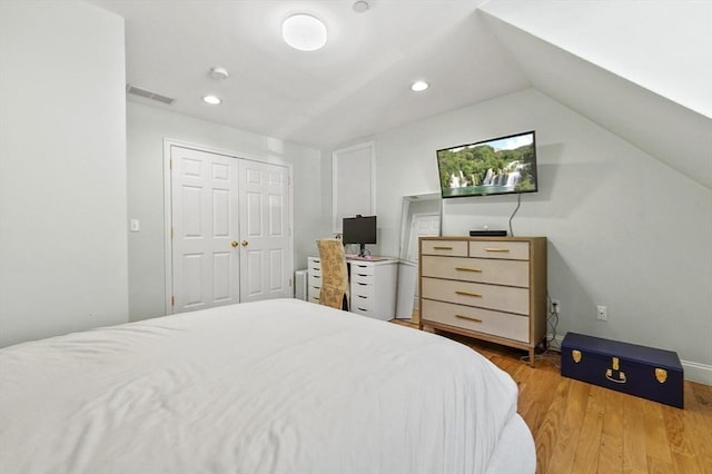 bedroom with vaulted ceiling, a closet, wood finished floors, visible vents, and recessed lighting