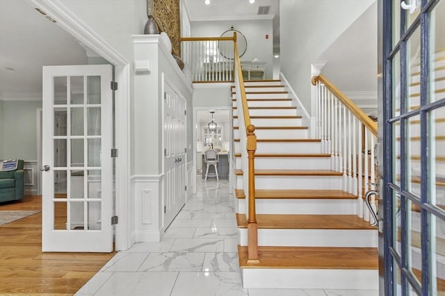 stairs featuring french doors, ornamental molding, marble finish floor, a towering ceiling, and visible vents