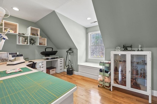 office space featuring baseboards, visible vents, vaulted ceiling, and light wood-type flooring