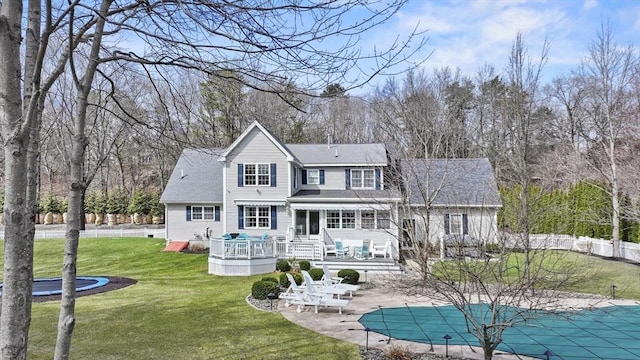 rear view of property featuring fence, a fenced in pool, a deck, a lawn, and a patio area