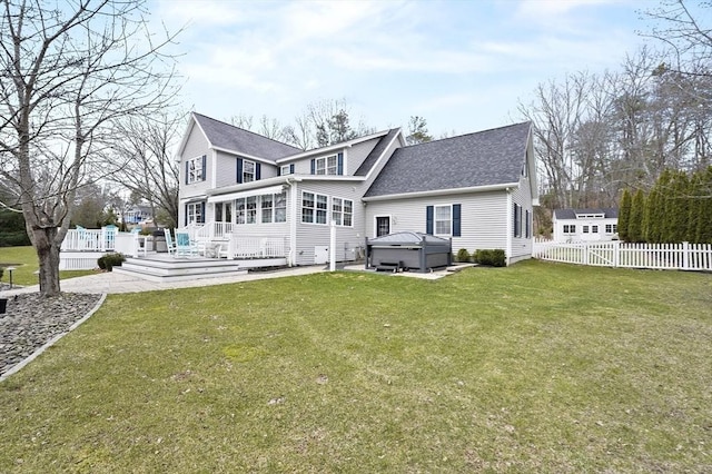 rear view of house featuring roof with shingles, fence, a hot tub, a sunroom, and a lawn