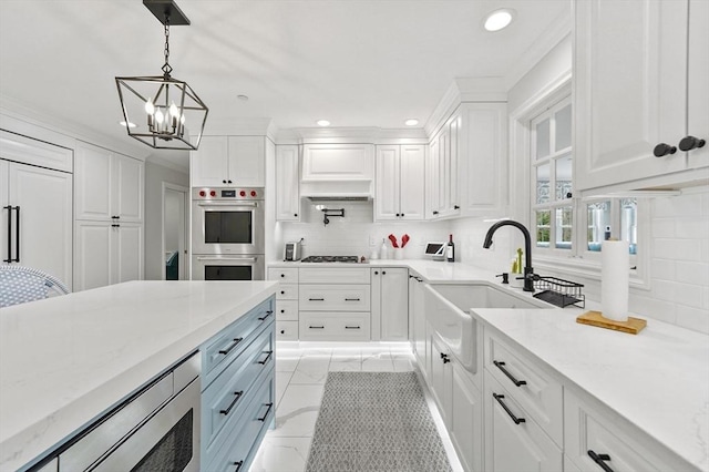 kitchen featuring white cabinetry, an inviting chandelier, a sink, pendant lighting, and appliances with stainless steel finishes