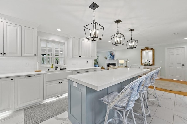 kitchen featuring decorative backsplash, a breakfast bar, a kitchen island, white cabinetry, and a sink