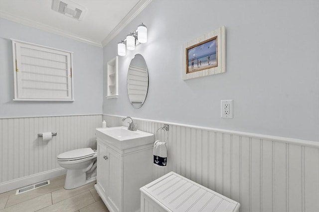 bathroom with a wainscoted wall, visible vents, toilet, and ornamental molding