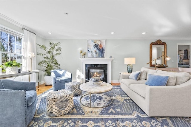 living area featuring crown molding, baseboards, wood finished floors, recessed lighting, and a glass covered fireplace