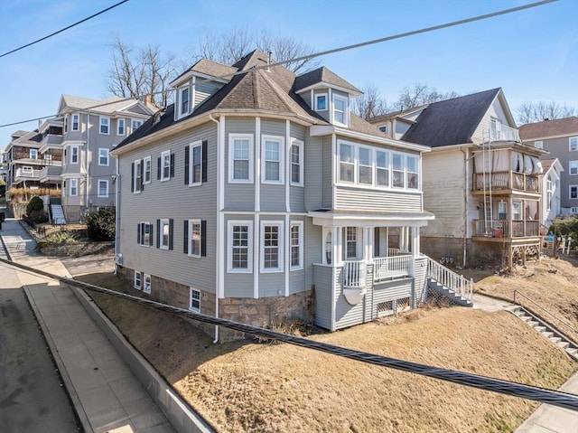 view of front of property featuring covered porch, a residential view, and roof with shingles