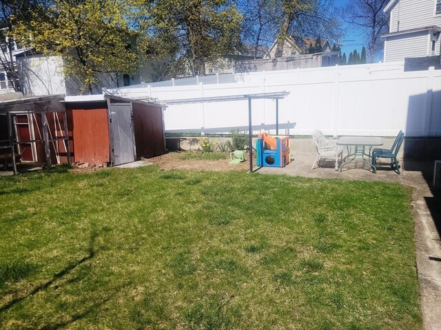 view of yard featuring a storage unit, a patio area, an outbuilding, and fence
