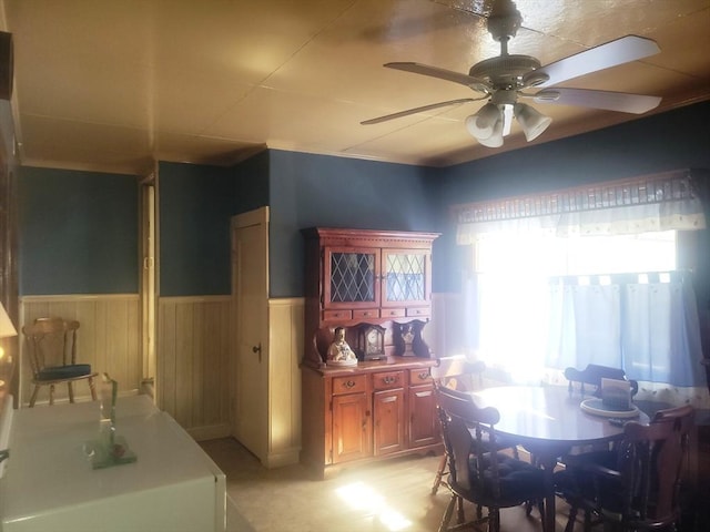 dining space with wainscoting and a ceiling fan