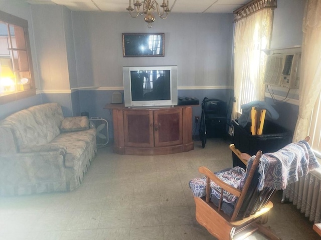 living room with plenty of natural light, a wainscoted wall, a paneled ceiling, and light floors