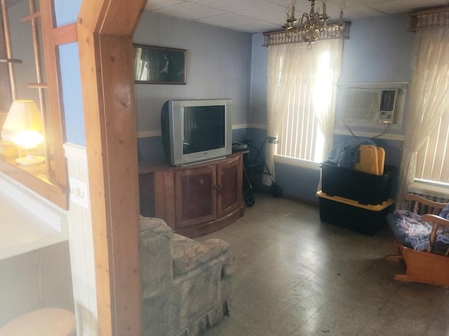 living area featuring tile patterned floors, a wall mounted AC, and a drop ceiling