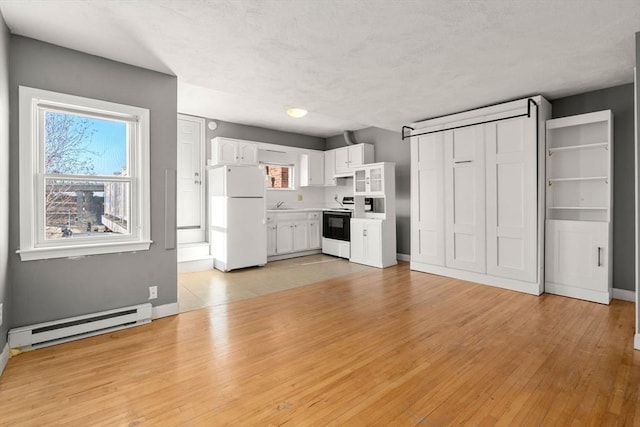 kitchen featuring light countertops, baseboard heating, light wood-style flooring, white cabinets, and white appliances