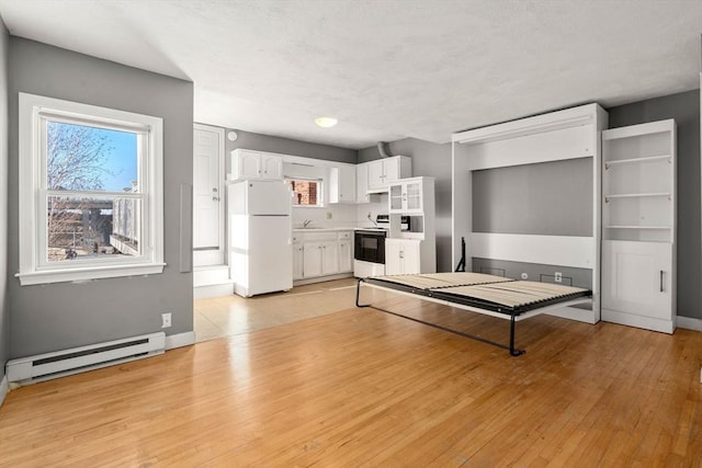 kitchen featuring a baseboard heating unit, freestanding refrigerator, light wood-style floors, electric range, and white cabinetry