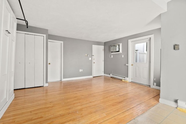 foyer entrance featuring a wall mounted air conditioner, baseboards, baseboard heating, and light wood finished floors