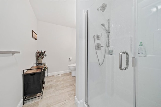 bathroom featuring toilet, baseboards, and a stall shower