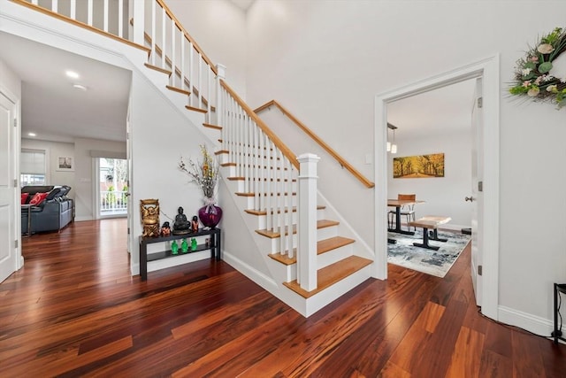 stairway featuring hardwood / wood-style flooring, recessed lighting, baseboards, and a towering ceiling