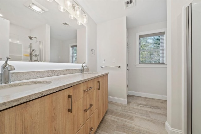 bathroom with a walk in shower, visible vents, and a sink