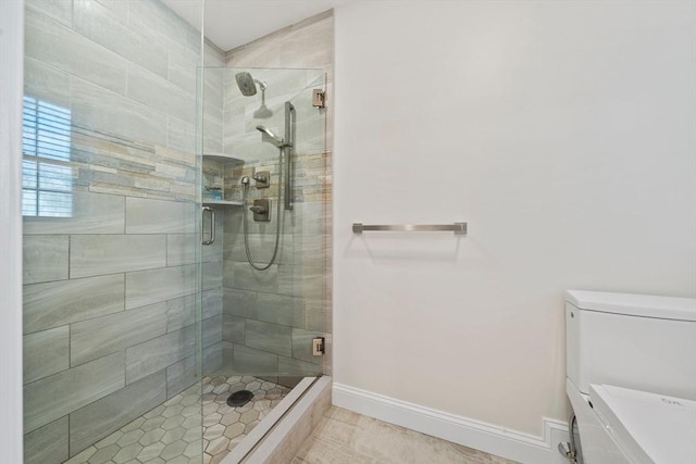 bathroom featuring a shower stall, toilet, and baseboards