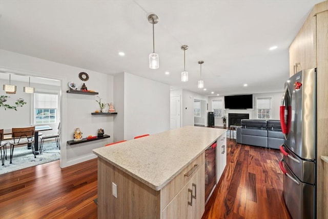 kitchen featuring a kitchen island, dark wood-type flooring, light brown cabinets, and freestanding refrigerator