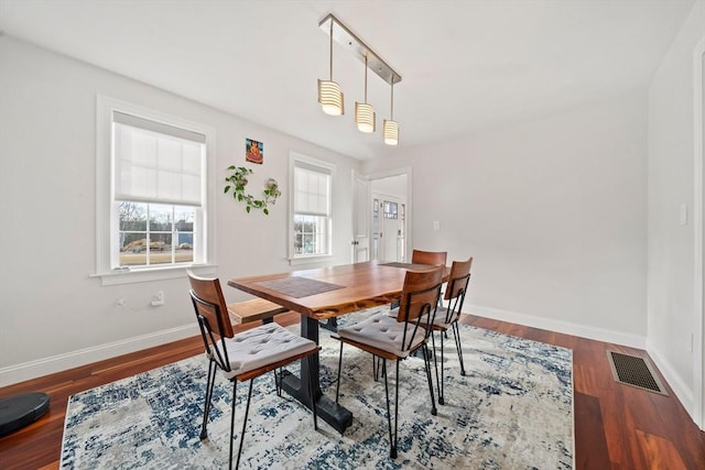 dining area featuring visible vents, baseboards, and wood finished floors