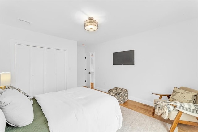 bedroom with wood finished floors, baseboards, and a closet