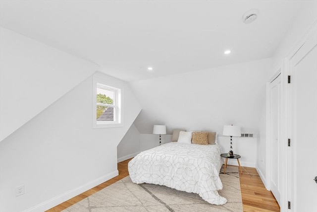 bedroom with wood finished floors, vaulted ceiling, baseboards, and recessed lighting