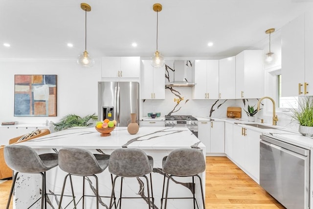 kitchen with stainless steel appliances, a sink, a kitchen island, light stone countertops, and a breakfast bar area