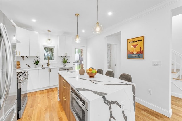 kitchen with appliances with stainless steel finishes, a sink, a center island, white cabinetry, and recessed lighting