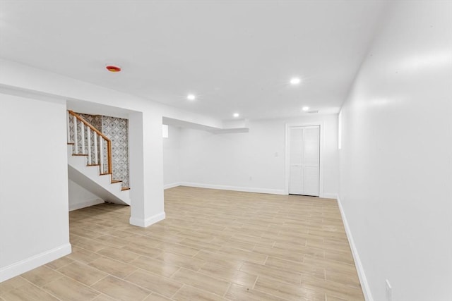 finished below grade area featuring recessed lighting, baseboards, stairway, and light wood finished floors