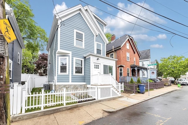 view of front of house with a fenced front yard and central AC