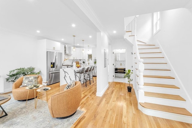 living room featuring ornamental molding, recessed lighting, stairs, baseboards, and light wood-type flooring