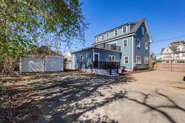 rear view of house featuring a garage, fence, and an outbuilding