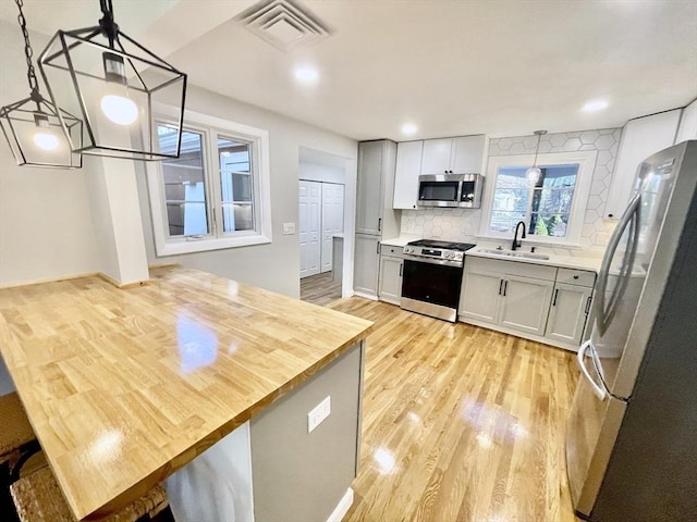17 Brentwood Rd, Sudbury, MA 01776 - kitchen featuring light wood-style flooring, backsplash, visible vents, stainless steel appliances, and a sink