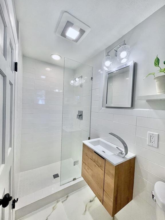 17 Brentwood Rd, Sudbury, MA 01776 - bathroom with visible vents, tile walls, vanity, marble finish floor, and a stall shower