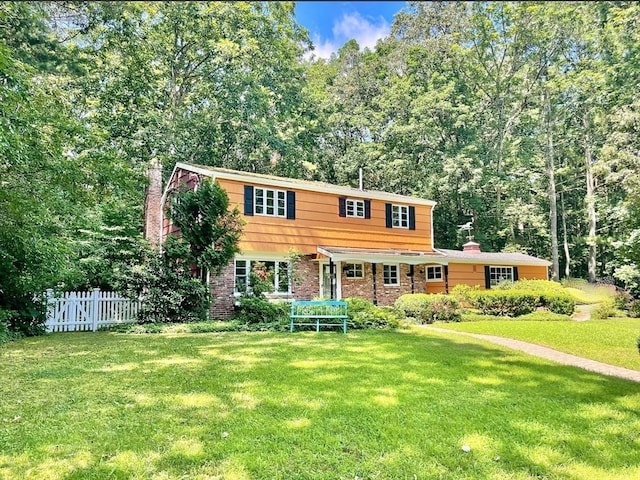 17 Brentwood Rd, Sudbury, MA 01776 - view of front of house featuring a front yard, fence, brick siding, and a chimney