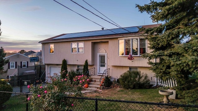 bi-level home featuring solar panels and a garage