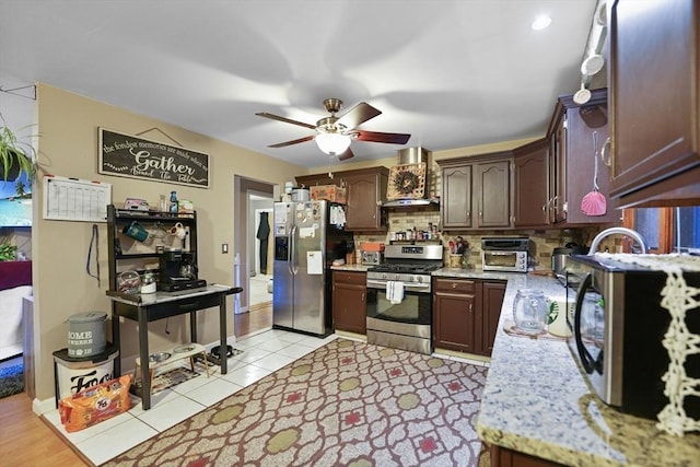 kitchen with wall chimney range hood, ceiling fan, tasteful backsplash, dark brown cabinetry, and stainless steel appliances