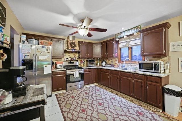 kitchen with decorative backsplash, appliances with stainless steel finishes, sink, wall chimney range hood, and light tile patterned flooring