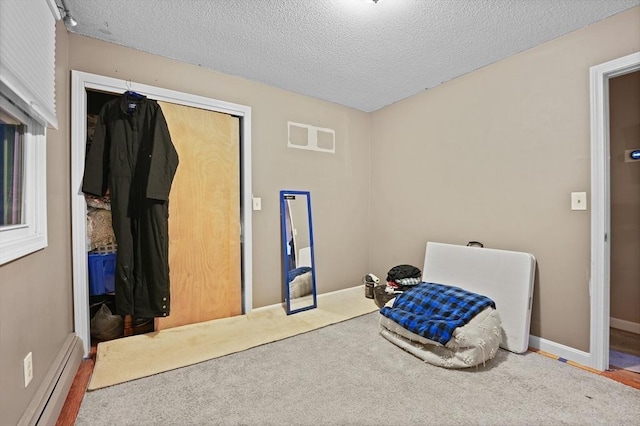 carpeted bedroom featuring a textured ceiling, a closet, and baseboard heating