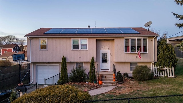 split foyer home featuring a garage, a front yard, and solar panels