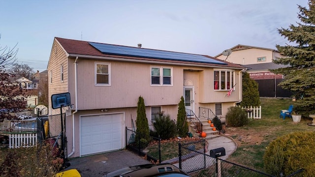 view of front of property featuring a garage, a front yard, and solar panels