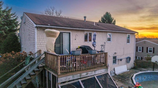 back house at dusk featuring a pool side deck