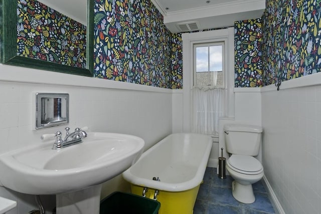 bathroom featuring a bathtub, tile patterned floors, sink, toilet, and tile walls