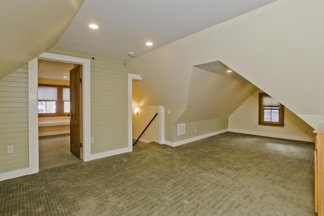 bonus room featuring plenty of natural light, dark carpet, and lofted ceiling