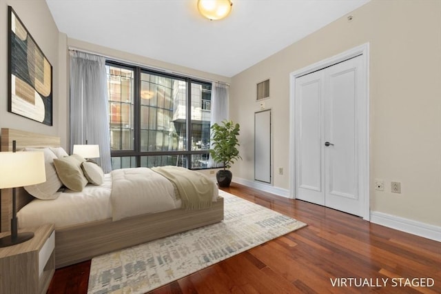 bedroom featuring wood finished floors, visible vents, a closet, and baseboards