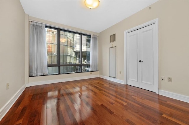 unfurnished bedroom with visible vents, baseboards, a closet, and hardwood / wood-style flooring