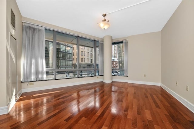 unfurnished room with visible vents, baseboards, and wood-type flooring